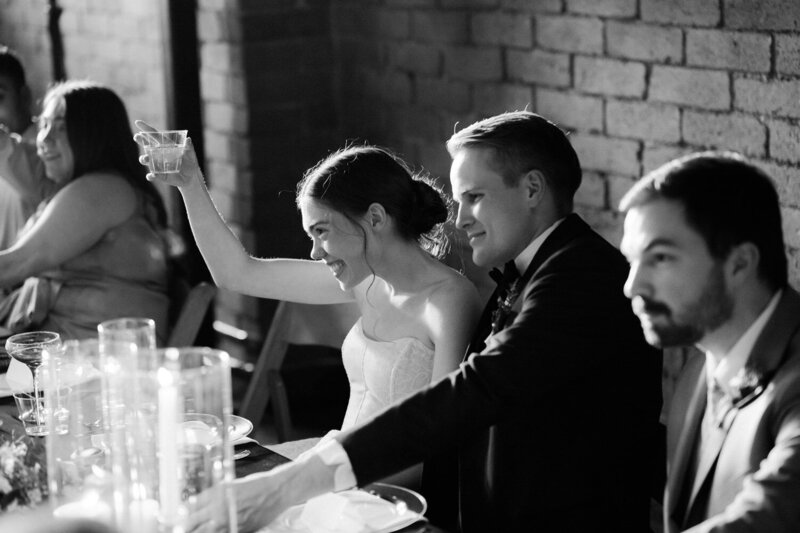 Bride raises a glass to the toast giver during the wedding reception
