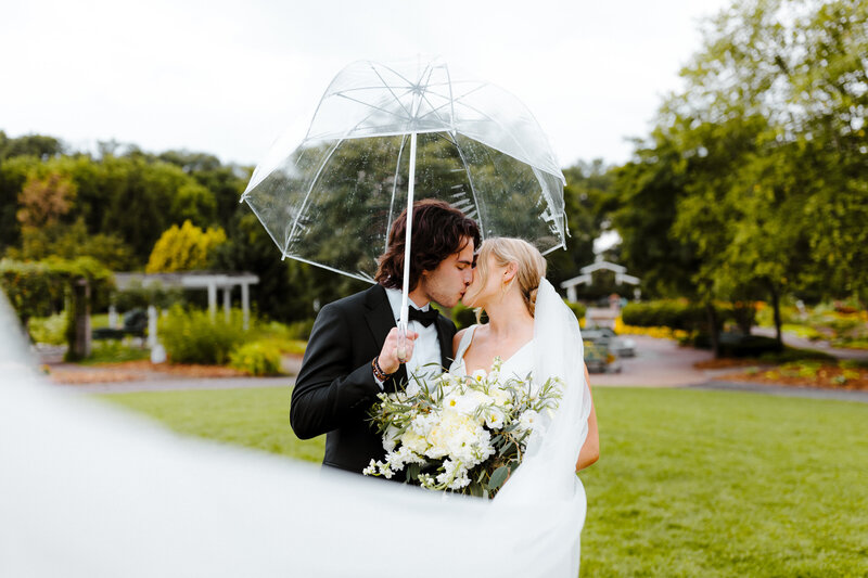 Bride and Groom kissing under an umbrella in the rain in Minneapolis