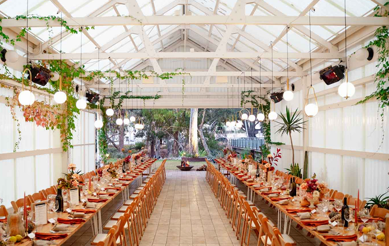 A white wedding reception venue with exposed rafters and wedding reception tables