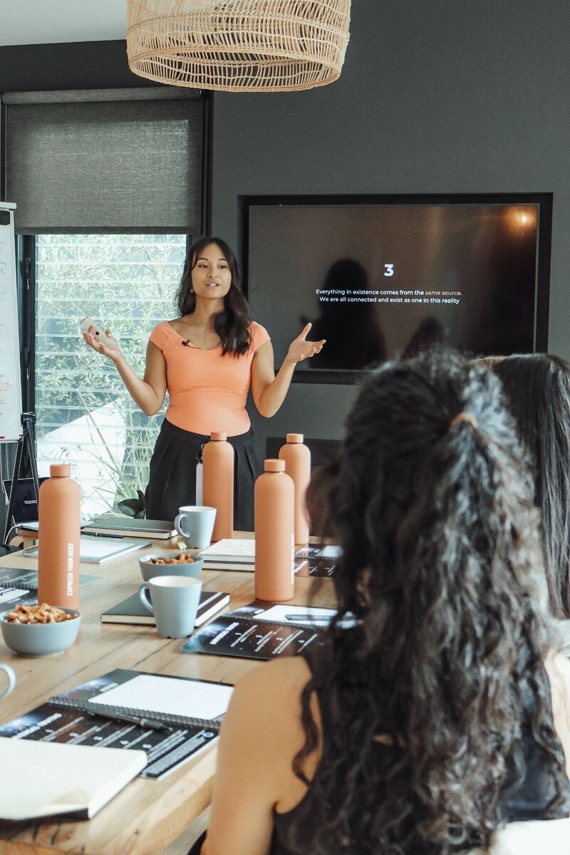 Trang delivering a presentation in a board room of women. 