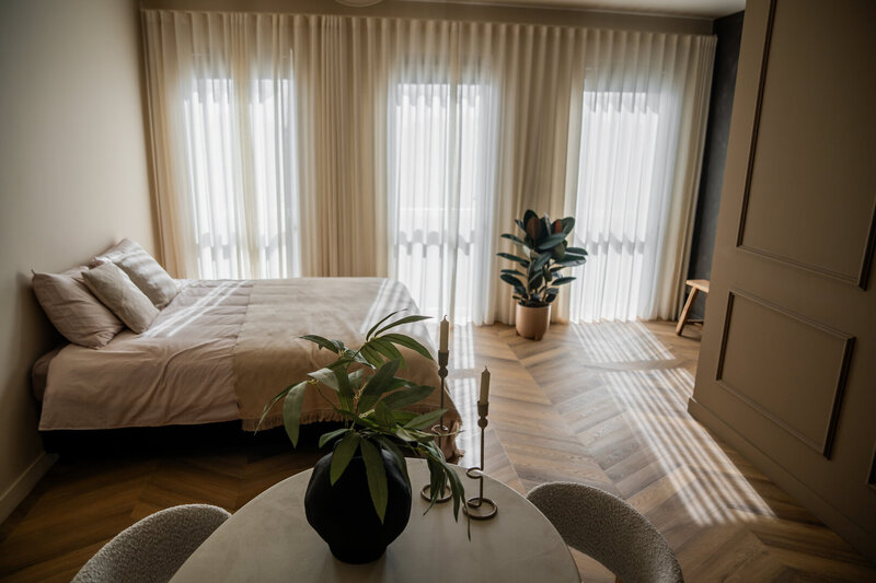 Sfeervolle slaapkamer setting in Studio Laurant, verlicht door prachtig natuurlijk daglicht dat zacht naar binnenvalt.