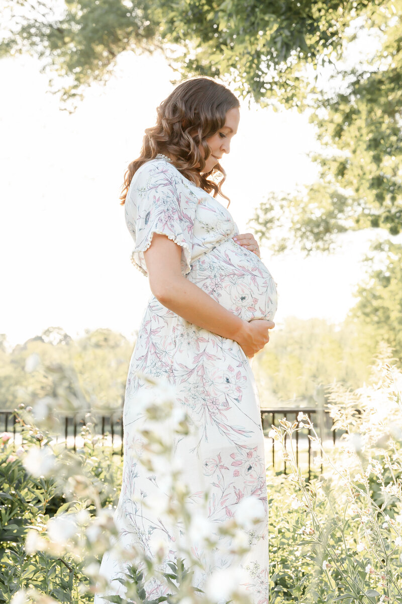 Maternity session with mother holding belly in a side profile and backlit