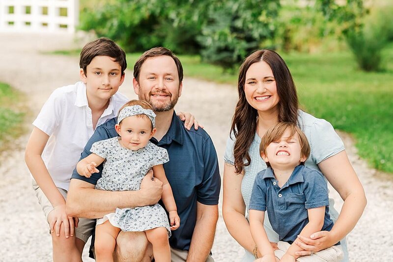 Family squatting on white stone for family photography.