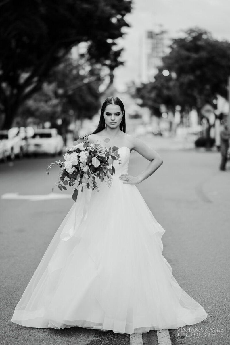 bride holding her bridal bouquet with her hand on her hop standing in a street