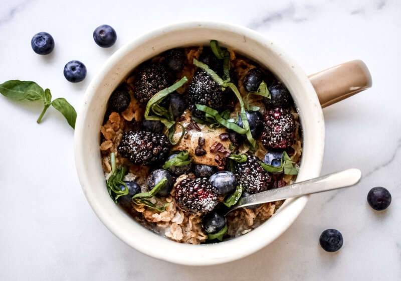A top shot of a blackberry bowl with oatmeal and scattered blue berries.