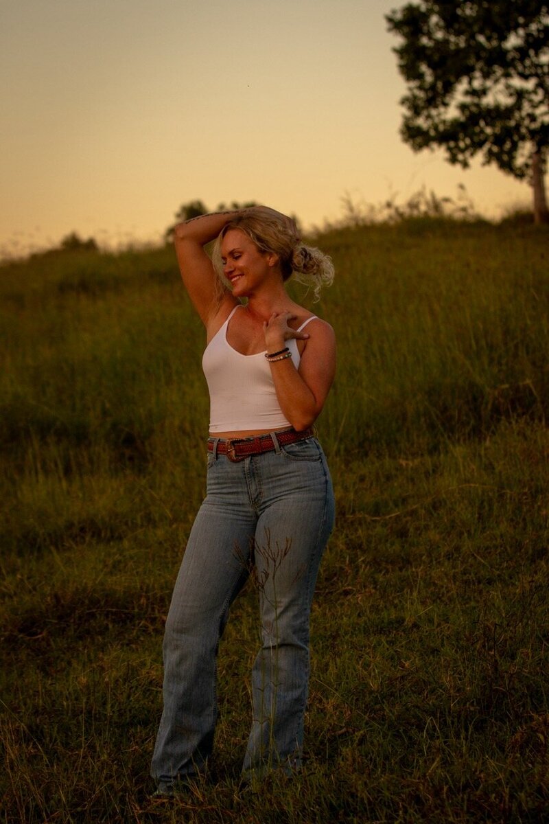 Woman standing in field embracing her beauty and her own Goddess Within.