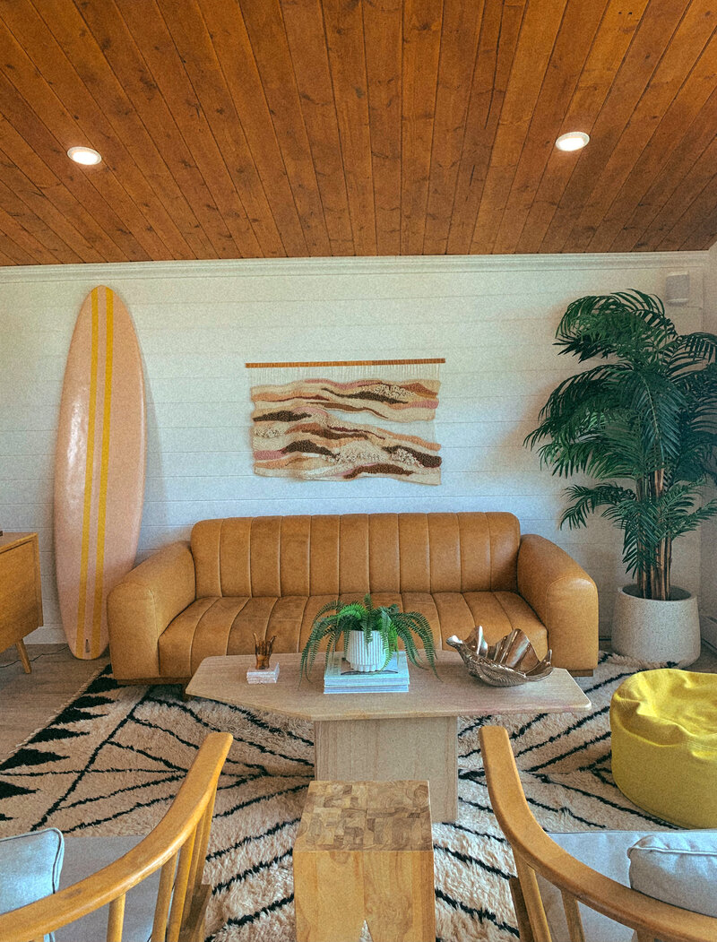 Bright modern San Diego living room with surfboard décor, mid-century furniture, and coastal styling — lifestyle imagery for Mary Pernicano Real Estate.”