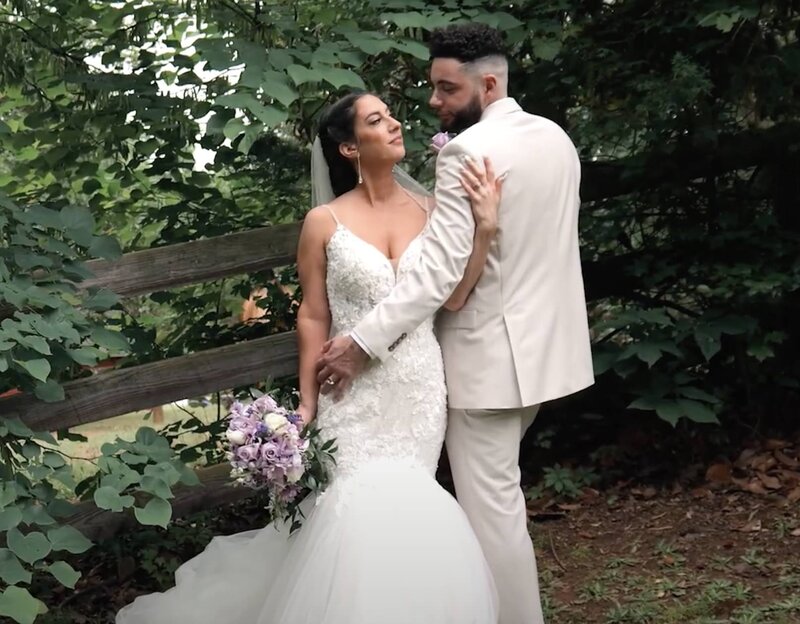 A newlywed couple facing opposite ways with their arms around each other 