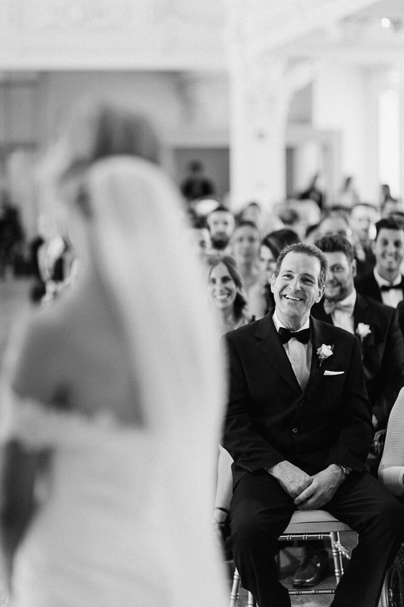 Le père de la mariée regarde sa fille, le regard plein d'admiration pendant la cérémonie de mariage.