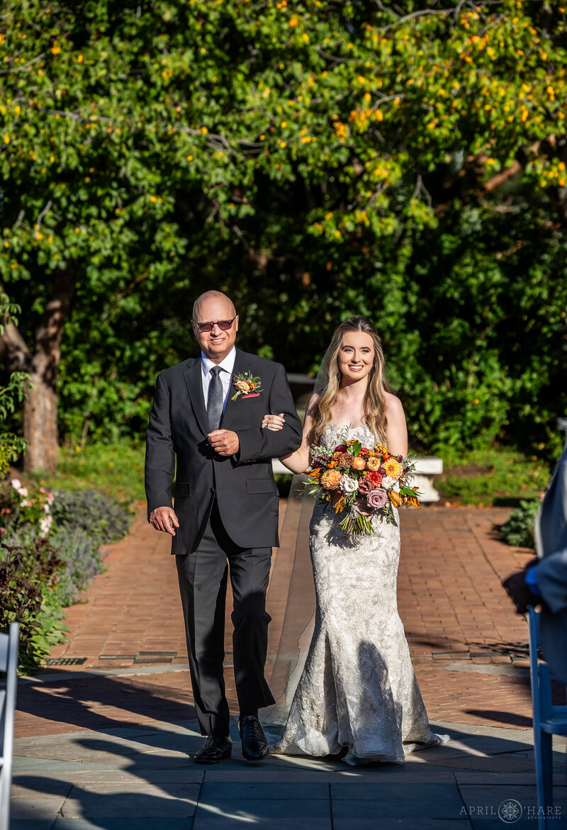 Bride and her father walk down the aisle  in the Romantic Gardens at Denver Botanic Gardens