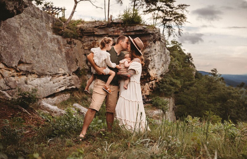 Family portrait of parents kissing while holding children