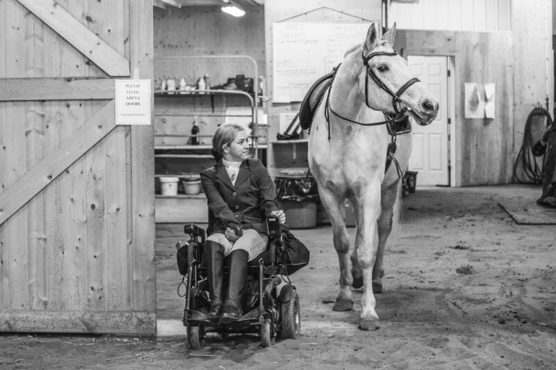 girl in wheelchair beside her horse