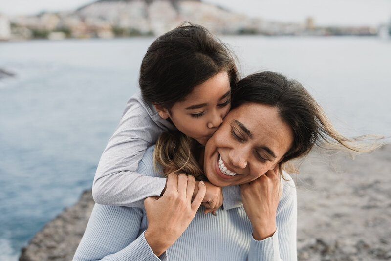 Daughter warmly hugging her mother, both smiling, symbolizing care and support—representing the compassionate solutions offered by Occam Health.