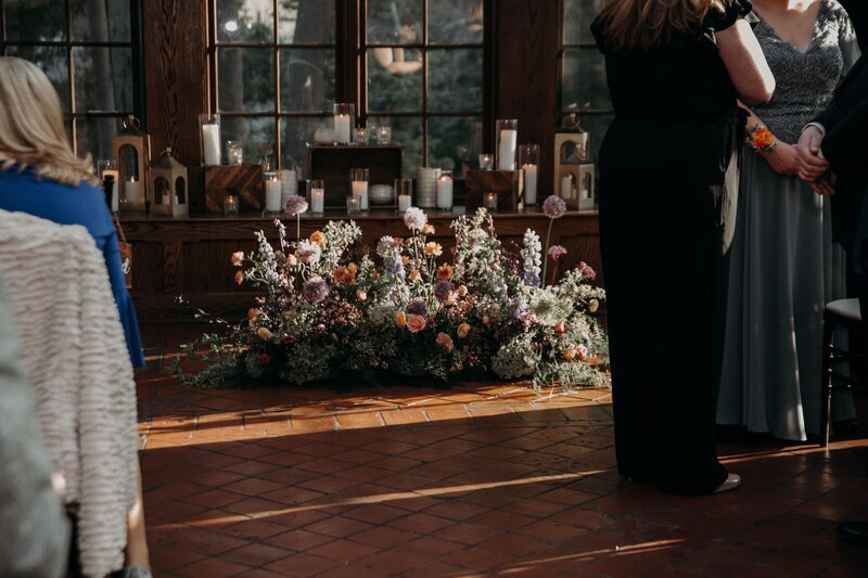 Textural floral installation on the floor, featuring roses, delphinium, and lisianthus in lavender, pink, and blush tones.