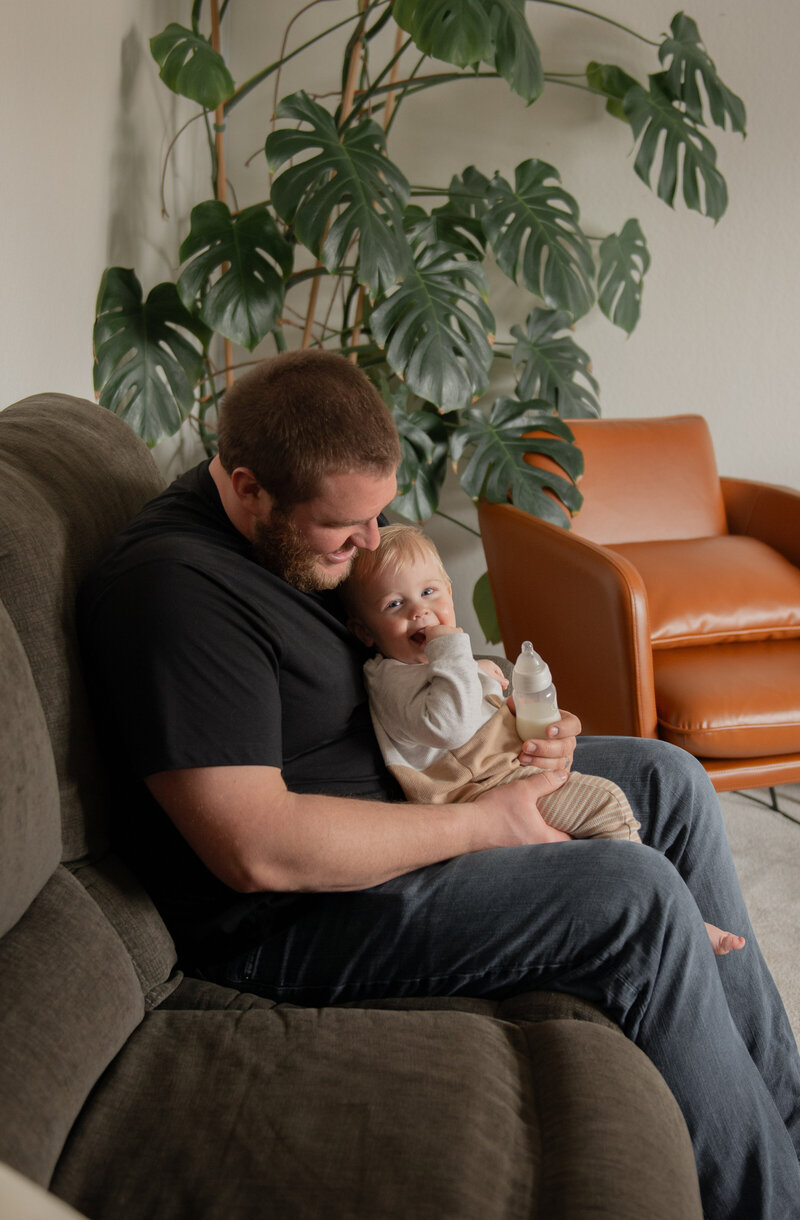 father smiling down at his son holding bottle