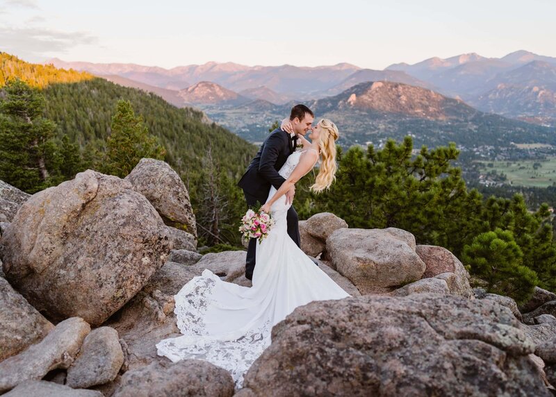 Bride and groom sharing a romantic kiss on the rocky summit of Kruger Rock in Estes Park, Colorado, captured by a professional Colorado elopement videographer Alpine Vows with mountain views in the background.