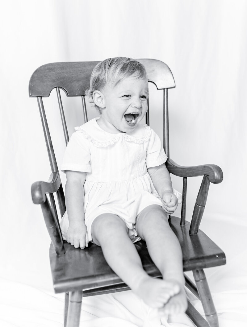 A classic heirloom children's portrait featuring a young toddler with golden hair and bright blue eyes, dressed in a traditional light blue outfit. Timeless children's photography with a soft, painterly background.