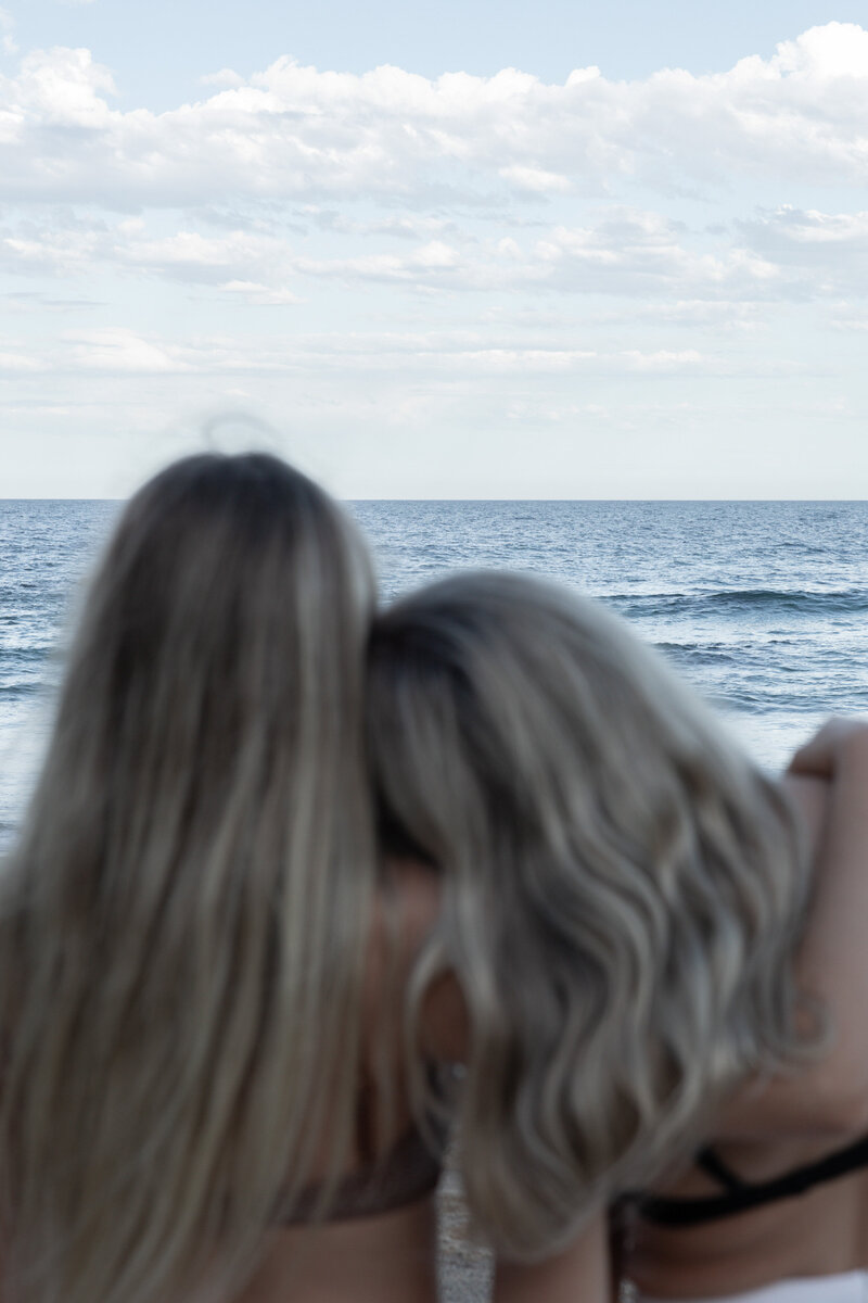 Two women sitting together at the beach
