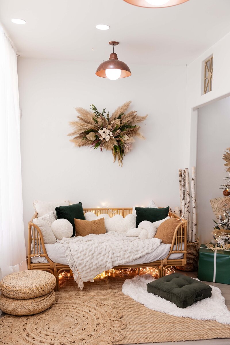 Holiday boho set at a photography studio with rattan daybed and cozy hygge feel.
