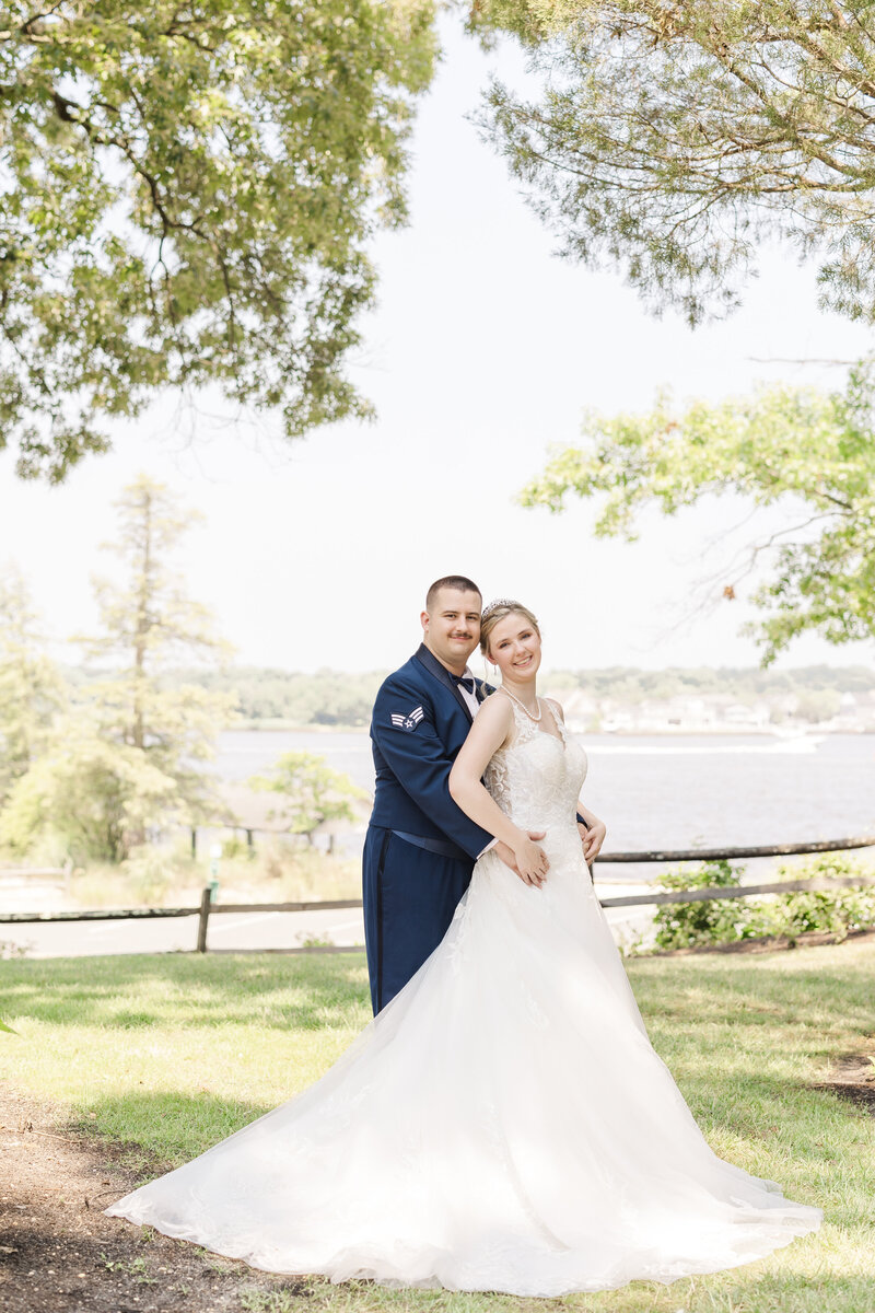 Newlyweds dance in a field in a blue suit and lace dress holding a colorful bouquet and laughing for a Detroit Wedding Photographer