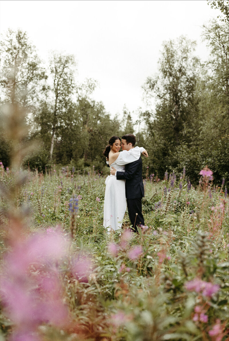 couple  wrapped up around one another in a field of flowers