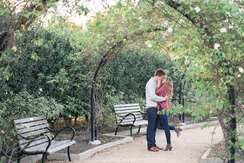 during their engagement session a couple kisses at McGovern Centennial Gardens groom kisses bride to be on a rooftop in downtown Houston by Swish and Click Photography