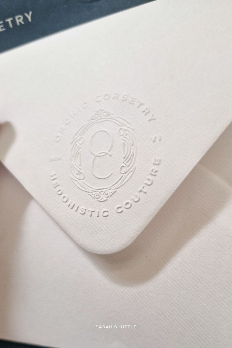 Embossed white envelope featuring the Orchid Corsetry emblem