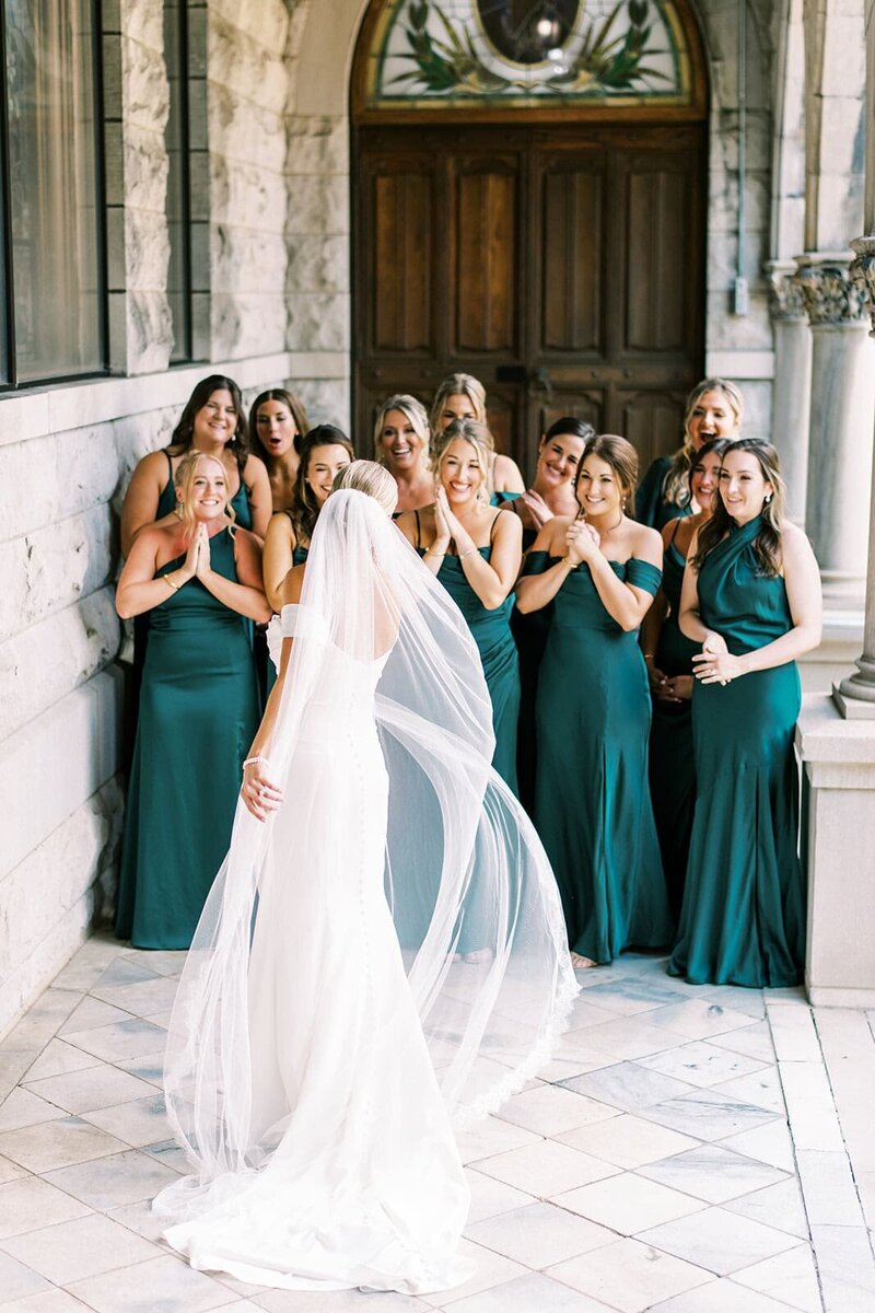 A bride reveals her wedding dress and veil to an excited bridal party during a fall wedding in Asheville, NC