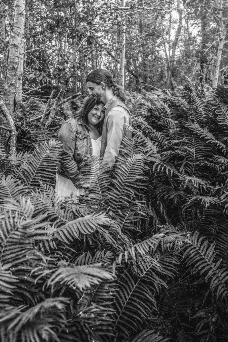 engaged couple embraces  in wild ferns