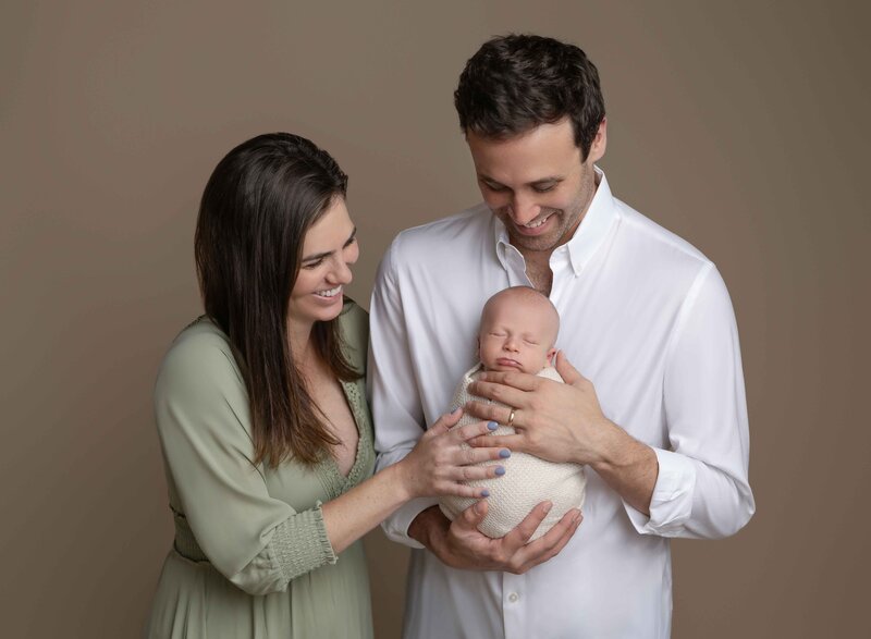 Mom and Dad smiling at baby. Photo taken at Marietta photography studio.