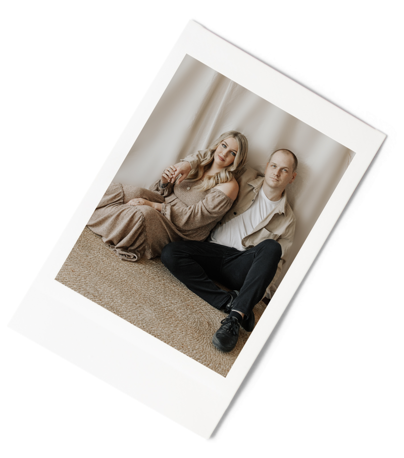 polaroid of man with arm over woman's shoulder sitting together on the floor