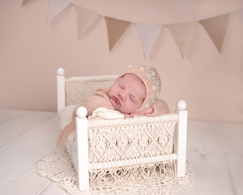 Nyfødt baby sover i liten makraméseng under fotografering i studio nær Oslo.