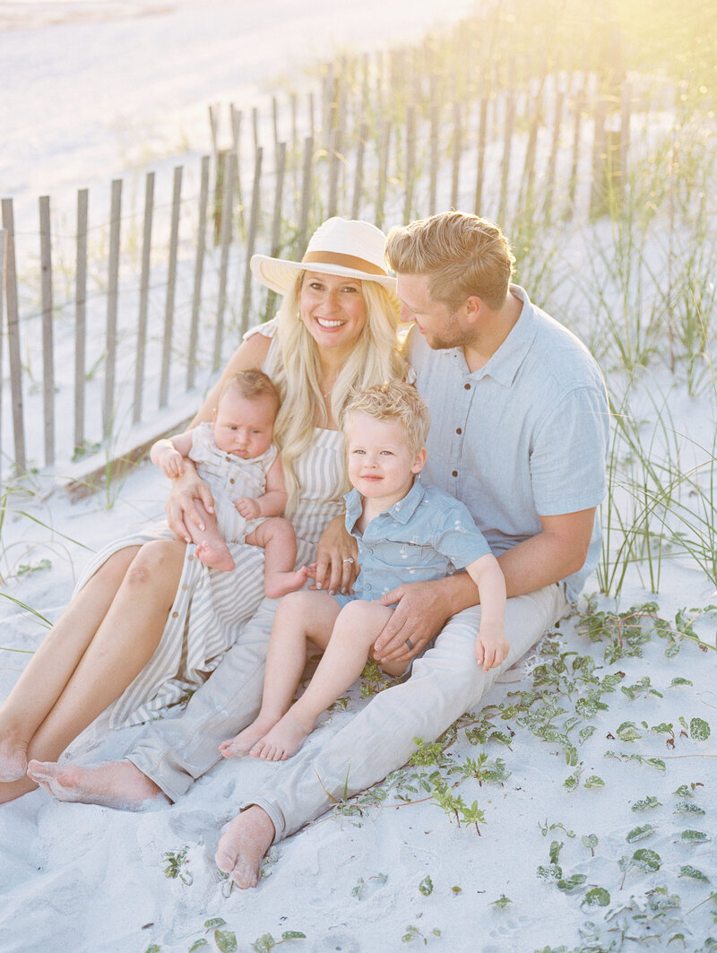 Family of four sitting together on the beach with ocean in the background