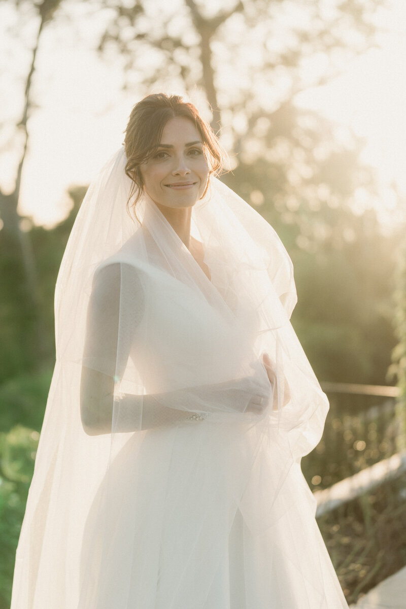 soft romantaic wedding photo of a bride wearing a white dress wrapped in a long veil during golden hour taken at el encanto a belmond hotel in santa barbara ca taken by magnolia west photography