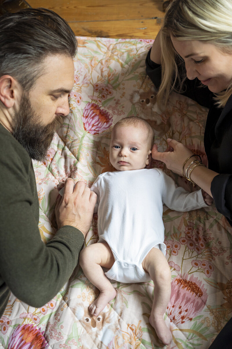 Mother and Father lying on the floor with their brand new baby girl during an at home photo shoot