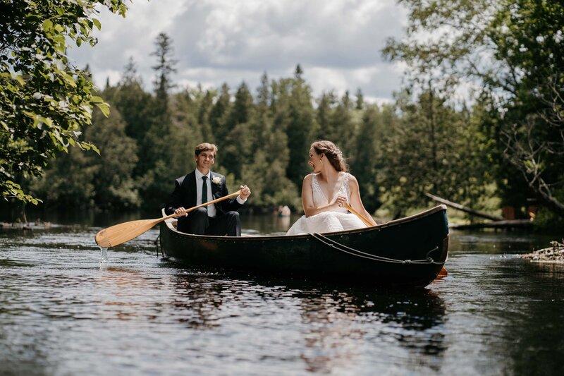 A bride and groom canoeing on their wedding day in the north woods