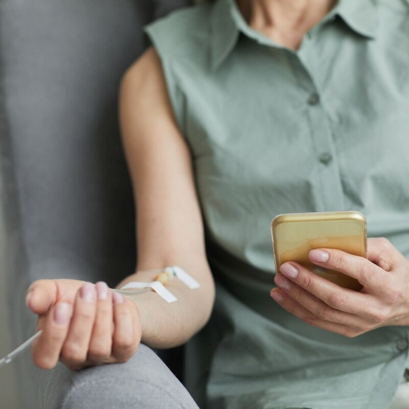 Patient Scrolling Phone during IV Infusion, St. Pete Rejuvenate Ketamine Therapy
