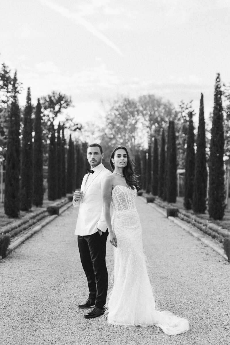 Portrait en noir et blanc d’un couple dans l’allée de cyprès du Château de Tourreau, photographié par Marion Pinel