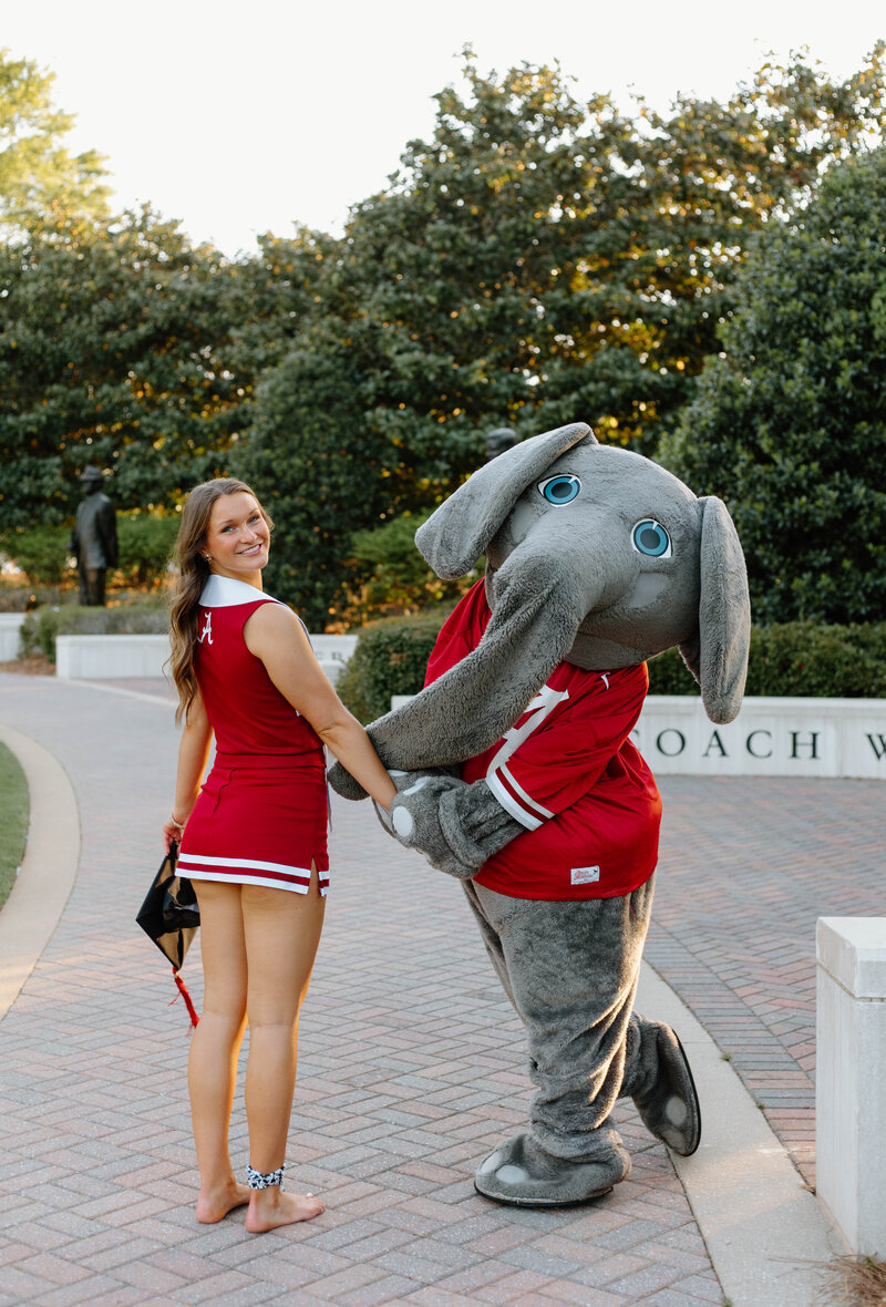 University of Alabama graduate holding big Als hand walking down the walk of champions