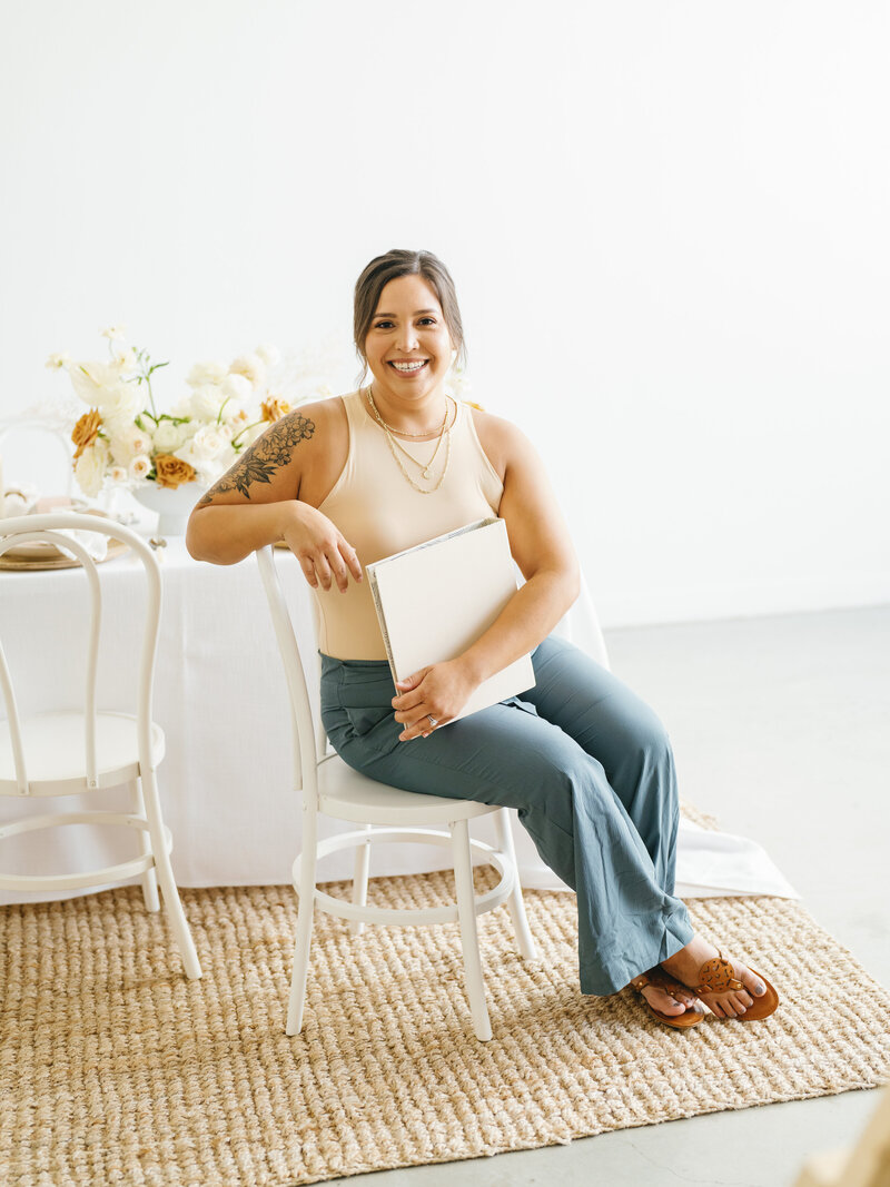 Eventive Designs lead planner smiling at a candlelit table set with blush stationery, soft florals, and neutral-toned decor, representing Austin wedding planning with a personal touch.