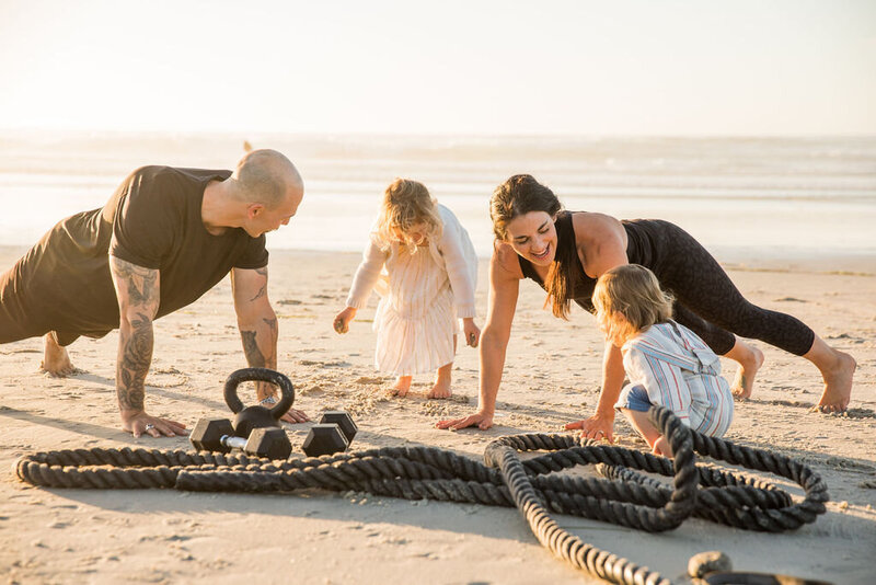 Jackie and Scott of Iron and Salt Fitness doing a beach family workout with their young kids.