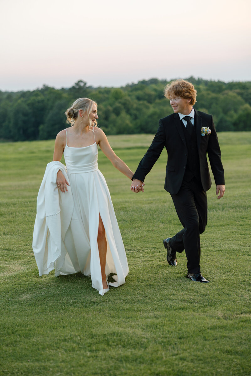 Bride and groom walk hand in hand at sunset