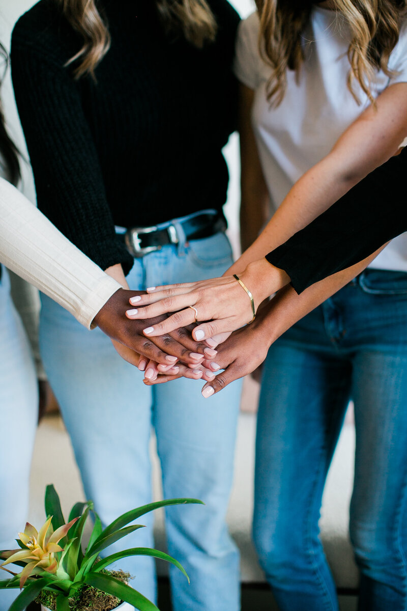 a group of women are putting their hands together in a circle to mean they are working as a team