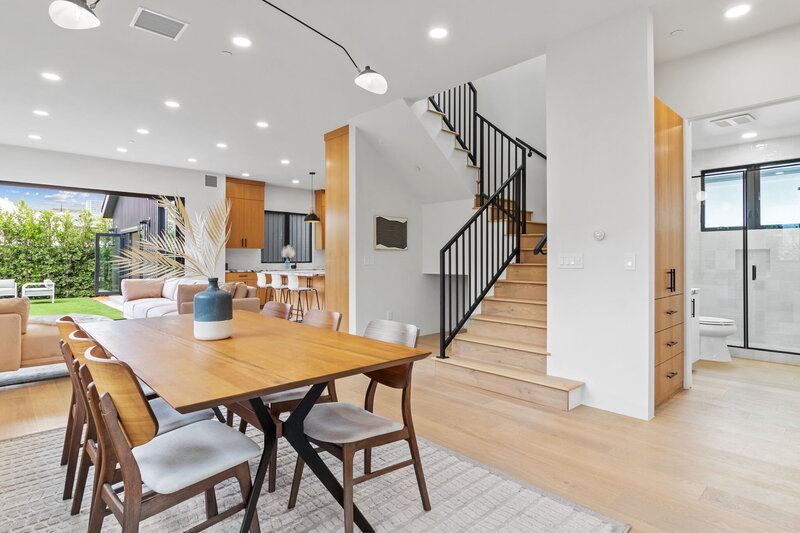 Interior view of a modern open-concept home renovation in Los Angeles featuring wood floors, custom cabinetry, iron staircase, indoor-outdoor flow, and updated kitchen—designed and built by AW Development Co.