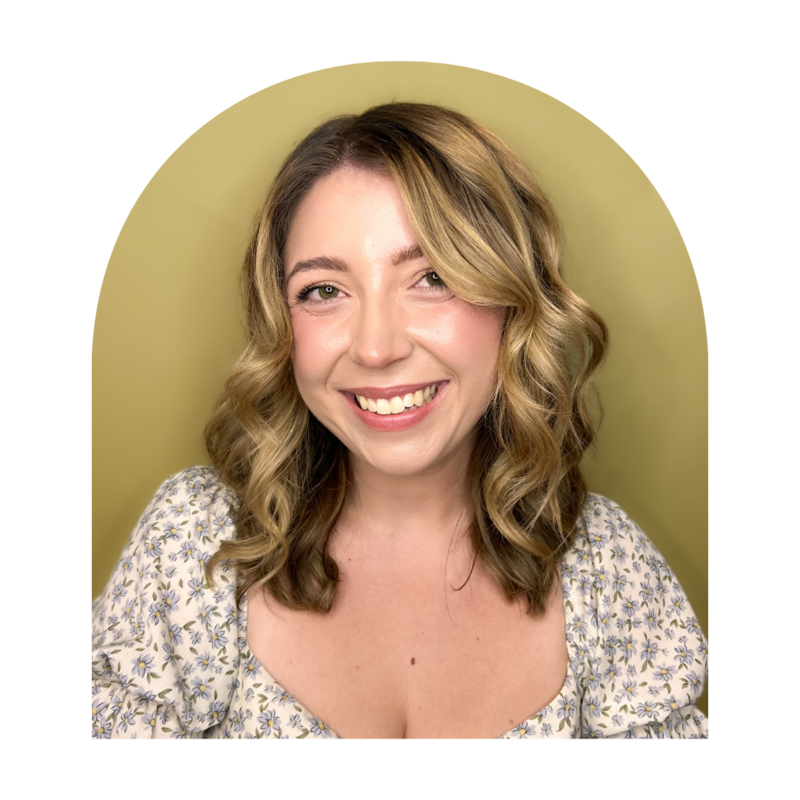 Blonde hair stylist, smiling with red lip stick, and a neutral background