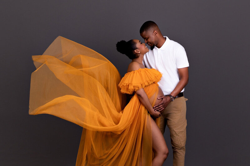 Couple maternity portrait with flowing mustard-yellow fabric