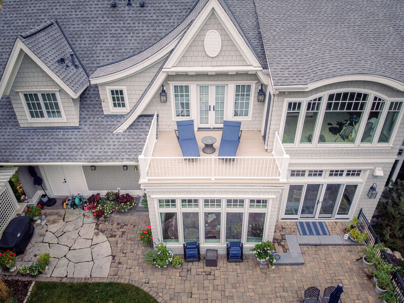 Low-maintenance PVC deck on top of a sunroom with blue lounge chairs. 