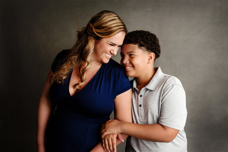 st-louis-family-photographer-mom-and-older-son-snuggled-together-on-gray-backdrop