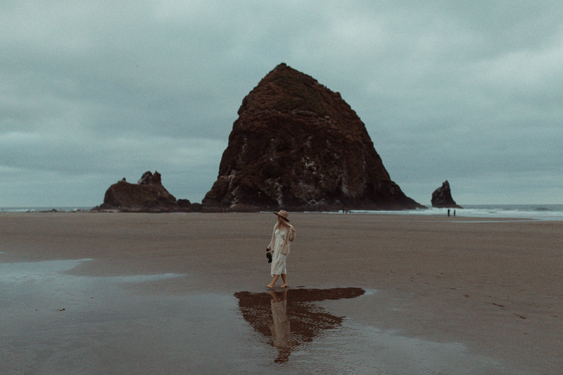 girl walking at Cannon Beach in Oregon, with champagne in her hand