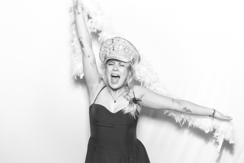 Guest during a wedding photo booth experience for a luxury event in the Oxfordshire, posing wearing curated props against a white backdrop